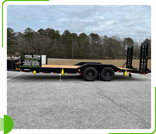 Flatbed trailer parked on a gravel lot with trees in the background.